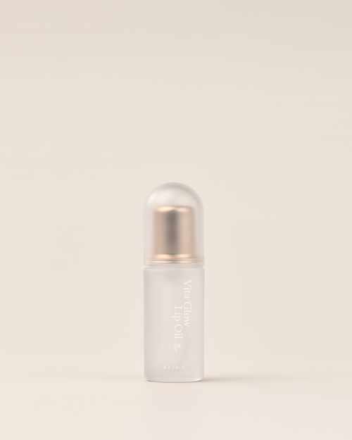AXIS-Y Vita Glow Lip Oil Lipgloss mit pflegender Textur in einem transparenten Flakon, auf einem weißen Hintergrund liegend